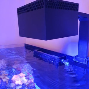 May include: A black aquarium light fixture with a honeycomb-shaped grill on top, mounted above a blue saltwater aquarium.