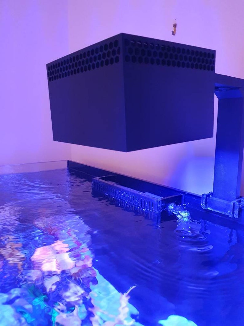 May include: A black aquarium light fixture with a honeycomb-shaped grill on top, mounted above a blue saltwater aquarium.