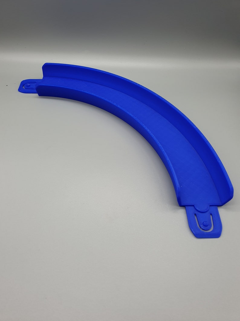 May include: A blue plastic track piece for a toy racing car track. The piece is curved and has a groove for the car to run in.