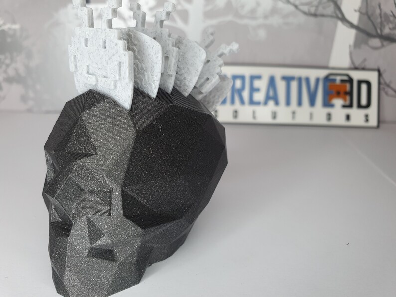Puede incluir: Un cr&aacute;neo negro geom&eacute;trico con un mohawk blanco y pixelado. El cr&aacute;neo est&aacute; hecho de un material impreso en 3D y tiene una superficie texturizada.