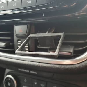 May include: A black plastic phone holder designed to fit into a car's air vent.