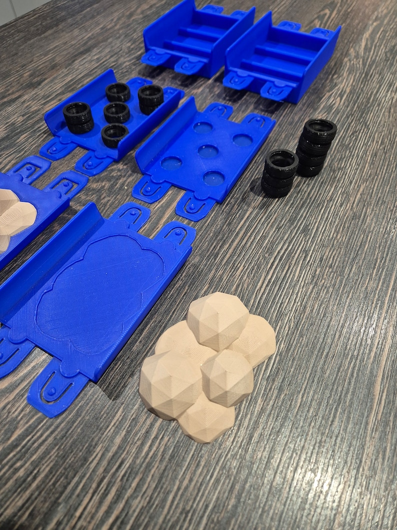 Puede incluir: Un conjunto de piezas de pista de pl&aacute;stico azul para un juego de coches de carreras de juguete. El conjunto incluye piezas de pista rectas, piezas de pista curvas y un puente. Tambi&eacute;n hay cuatro neum&aacute;ticos negros y cuatro rocas marrones.