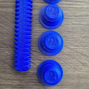 May include: Four blue plastic caps with the number "2" printed on them, and a blue plastic screw with a textured surface.