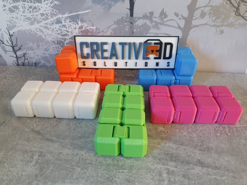 Op de afbeelding: Vijf verschillende fidget-speelgoedjes, elk gemaakt van een ander gekleurd plastic. De speelgoedjes zijn in een rij gerangschikt, met het witte speelgoedje in het midden. De speelgoedjes zijn allemaal gemaakt van zacht, flexibel plastic en hebben verschillende texturen. De speelgoedjes zijn allemaal ongeveer 12,5 cm lang en 5 cm breed. De speelgoedjes zijn allemaal gelabeld met de tekst "CREATIVE3D SOLUTIONS".