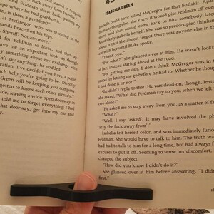 May include: A close-up of an open book with a black bookmark. The page is open to chapter 43, titled "Isabella Green". The text on the page discusses a conversation between two characters, Isabella and Blake, about a situation involving another character, McGregor.
