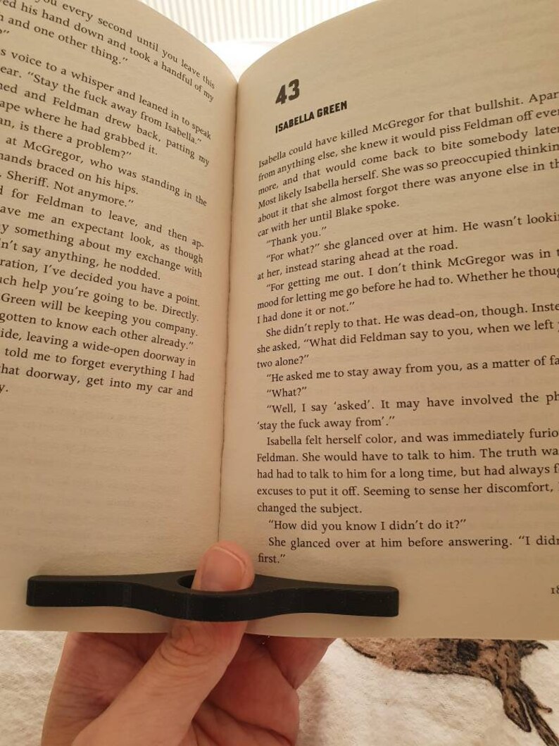 May include: A close-up of an open book with a black bookmark. The page is open to chapter 43, titled "Isabella Green". The text on the page discusses a conversation between two characters, Isabella and Blake, about a situation involving another character, McGregor.