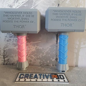 May include: Two gray plastic toy hammers with the inscription "WHOSOEVER HOLDS THIS HAMMER, IF SHE BE WORTHY, SHALL POSSESS THE POWER OF... THOR" and "WIHOSOEVER HOLDS THIS HAMMER, IF HE BE WORTHY, SHALL POSSESS THE POWER OF... THOR". One hammer has a pink handle and the other has a blue handle.