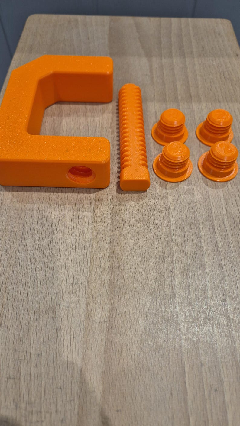 May include: Orange plastic clamp with a threaded screw, four orange plastic nuts, and a threaded rod.