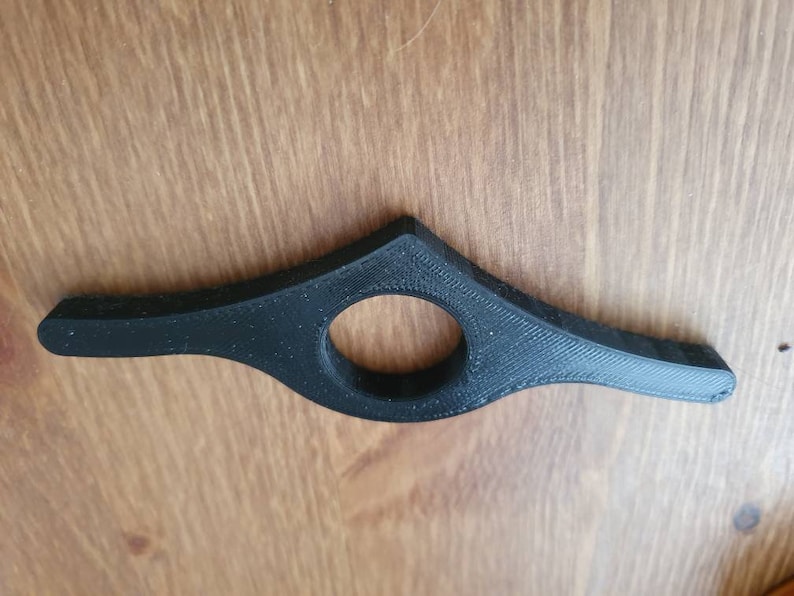 May include: A black plastic bookmark with a curved design and a round hole in the center.