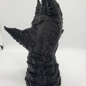 May include: A black 3D printed hand with long, sharp claws. The hand is posed with the fingers extended upwards.