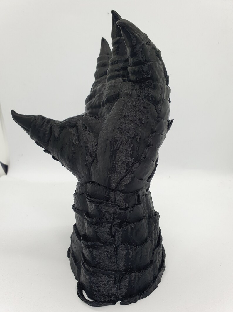May include: A black 3D printed hand with long, sharp claws. The hand is posed with the fingers extended upwards.
