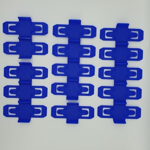K&ouml;nnte beinhalten: Ein Satz mit 15 blauen Plastikclips, angeordnet in drei Reihen zu f&uuml;nf. Die Clips sind dazu bestimmt, Gegenst&auml;nde zusammenzuhalten.