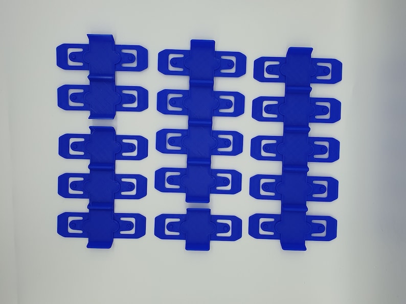 K&ouml;nnte beinhalten: Ein Satz mit 15 blauen Plastikclips, angeordnet in drei Reihen zu f&uuml;nf. Die Clips sind dazu bestimmt, Gegenst&auml;nde zusammenzuhalten.