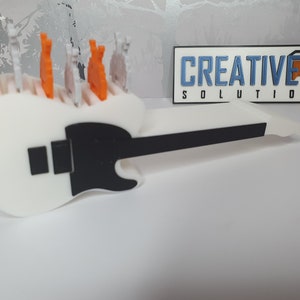 May include: White 3D printed guitar with a black pickguard and a black neck. The guitar has a row of small orange and white 3D printed figures on top.