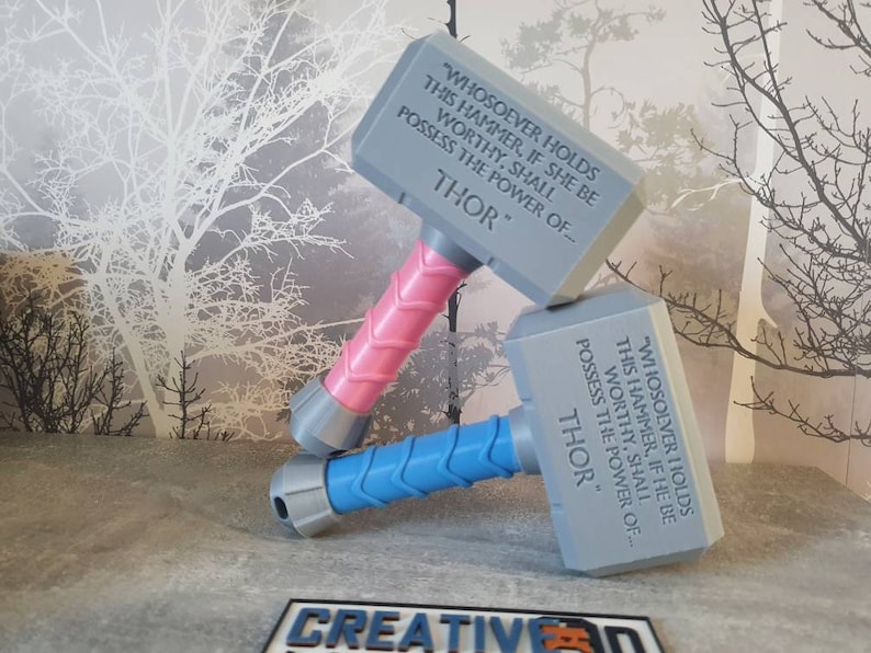 May include: Two gray plastic toy hammers with pink and blue handles. The hammers have the inscription "WHOSOEVER HOLDS THIS HAMMER, IF SHE BE WORTHY, SHALL POSSESS THE POWER OF... THOR" on them.