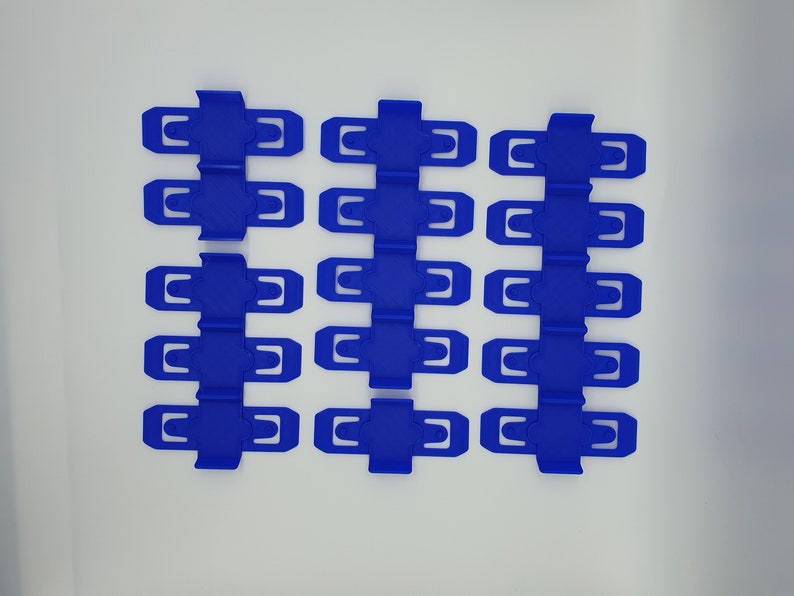 K&ouml;nnte beinhalten: Zw&ouml;lf blaue Plastikclips, angeordnet in vier Reihen zu je drei, auf wei&szlig;em Hintergrund.