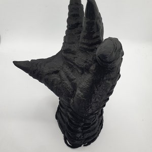 May include: A black 3D printed hand with long, sharp claws. The hand is posed in a grasping gesture, with the fingers curled inward.