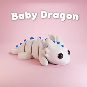 May include: A white baby dragon with blue spots and black eyes, lying on its belly on a pink background. The text "Baby Dragon" is written in white letters above the dragon.