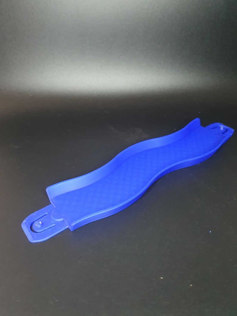 May include: A blue plastic track piece for a marble run toy. The track piece is curved and has a textured surface.