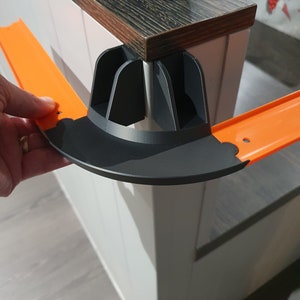 May include: Orange plastic track piece with a black plastic connector for a toy race track.