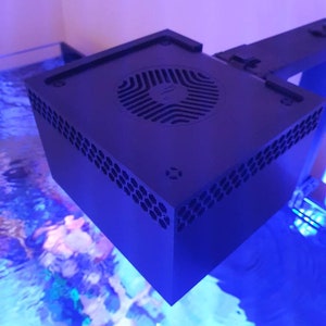 May include: A black square-shaped aquarium light with a fan on the top. The light is mounted on a black metal arm.