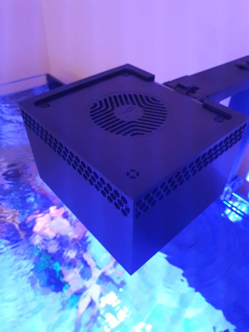 May include: A black square-shaped aquarium light with a fan on the top. The light is mounted on a black metal arm.