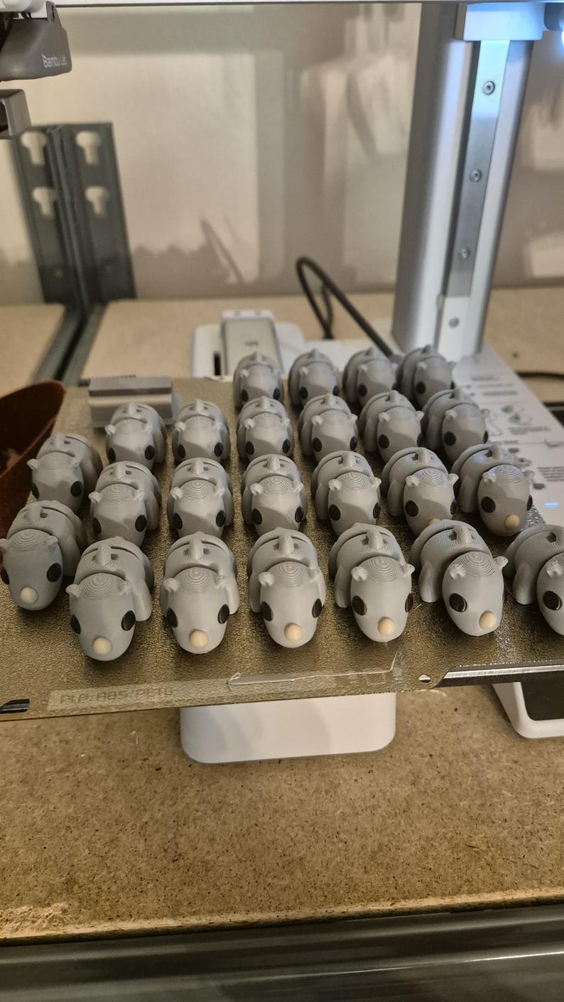 K&ouml;nnte beinhalten: Nahaufnahme einer Gruppe von 3D-gedruckten grauen Nashorn-Figuren auf einer wei&szlig;en Plattform. Die Plattform tr&auml;gt den Text "PLA ABS PLA".