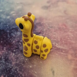 May include: A yellow and brown giraffe figurine with a segmented body. The giraffe has large black eyes and a brown mane.