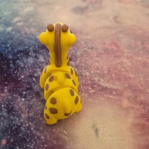 May include: A yellow giraffe toy with brown spots and a brown neck. The toy is made of a soft, pliable material and is designed to be squeezed.