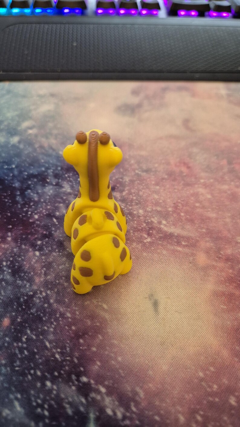 May include: A yellow giraffe toy with brown spots and a brown neck. The toy is made of a soft, pliable material and is designed to be squeezed.