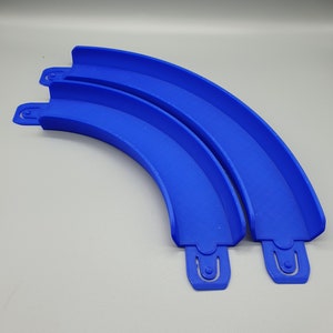 May include: Two blue plastic track pieces for a toy racing car track. The pieces are curved and connect together to form a longer track.
