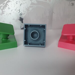May include: Three 3D printed square blocks, one green, one blue, and one pink. Each block has a small round knob on top.