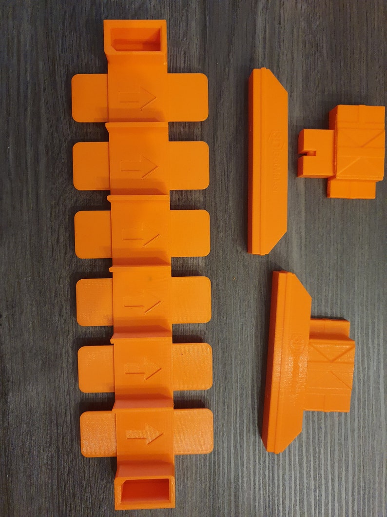 May include: Orange plastic track pieces for a toy car racing set. The track pieces include straight track, a curved track piece, and a track piece with a raised section.