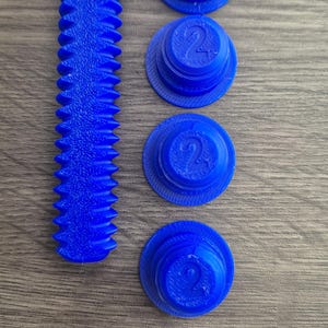 May include: Four blue plastic caps with the number "2" printed on them and a blue plastic screw with a threaded design.