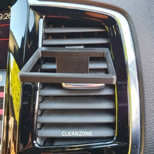Pu&ograve; includere: Un supporto per telefono nero in plastica per la griglia di ventilazione dell'auto con la scritta "CLEANZONE" stampata sulla griglia.