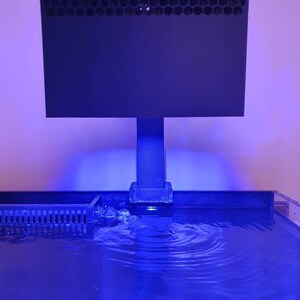 May include: A black rectangular aquarium filter with a honeycomb-shaped grill on top, mounted on a black stand above a blue lit aquarium.