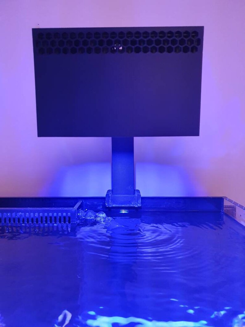 May include: A black rectangular aquarium filter with a honeycomb-shaped grill on top, mounted on a black stand above a blue lit aquarium.