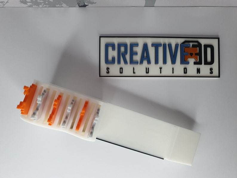 May include: A white plastic storage box with a sliding lid. The box is filled with small, colorful plastic blocks. The box is labeled "CREATIVE 3D SOLUTIONS".