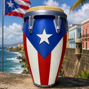 May include: A conga drum featuring the design of the Puerto Rican flag with a blue triangle, a white star, and alternating red and white vertical stripes. The drum has a tan head and a silver-colored metal rim with tension hardware.
