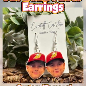 Puede incluir: Pendientes colgantes personalizados con una foto de una persona con una gorra de béisbol roja con el logo 'B'. Los pendientes son hipoalergénicos y tienen el texto "Fat Head Photo Earrings" y "Custom/Personal Dangles - Hypoallergenic".