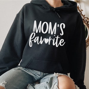 May include: A black hooded sweatshirt with the text "MOM'S favorite" in white with a small heart symbol.