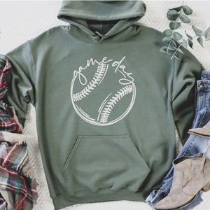 May include: A green hooded sweatshirt with a white baseball graphic and the text "game day" on the front.