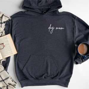 May include: A dark gray hooded sweatshirt with a white cursive inscription that reads "dog mom".