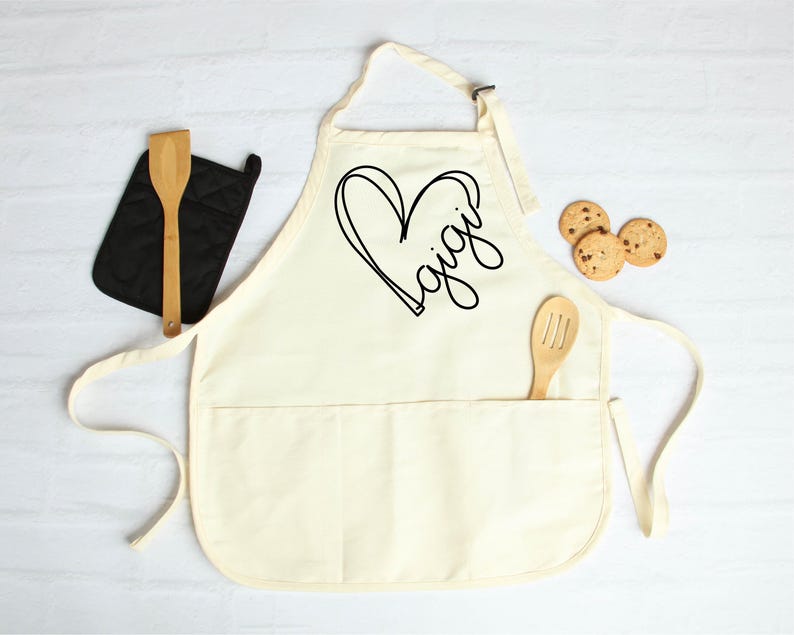 May include: A white cotton apron with a large black heart and the word "Gigi" written inside. The apron has a large pocket on the front.