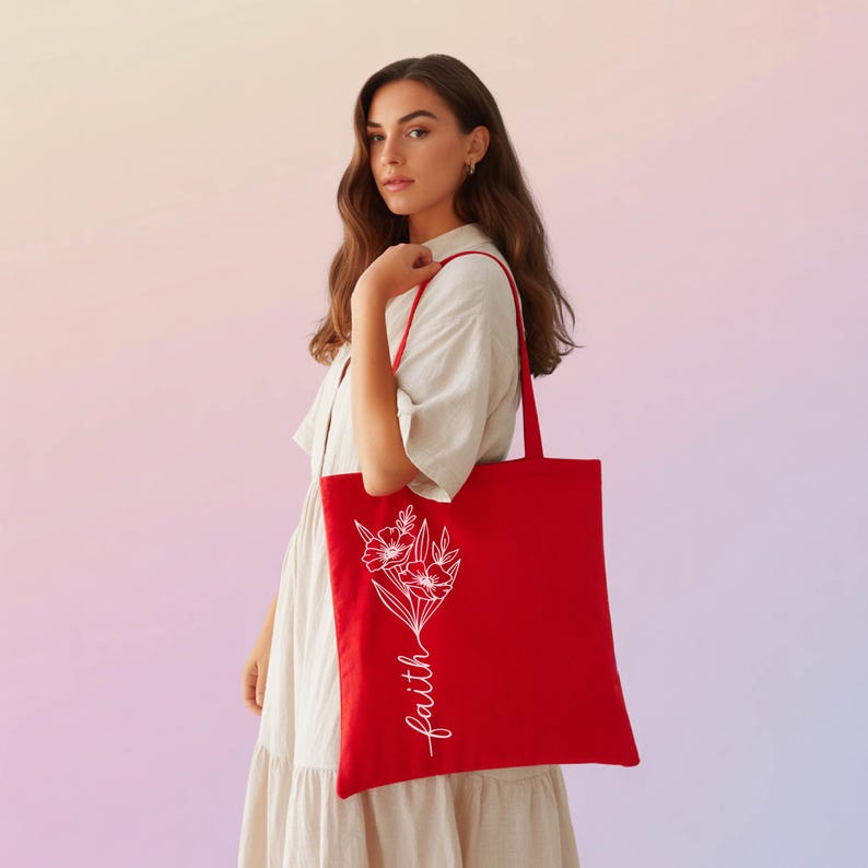 A woman in a white dress holding a red tote bag with the word "faith" printed on it.