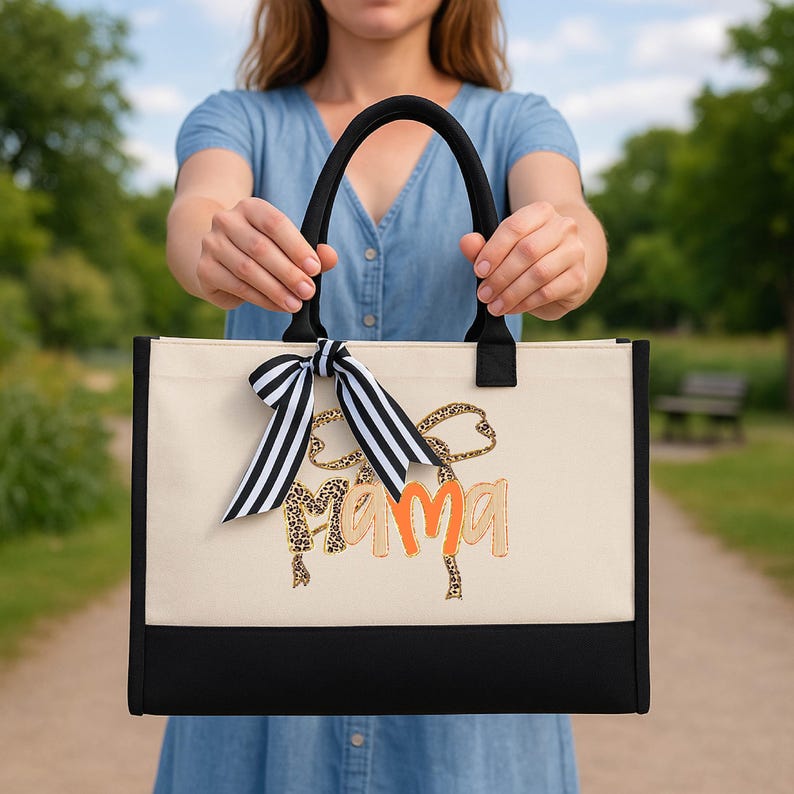 A woman holding a large tote bag with a leopard print design and the word "Mama" printed on it.