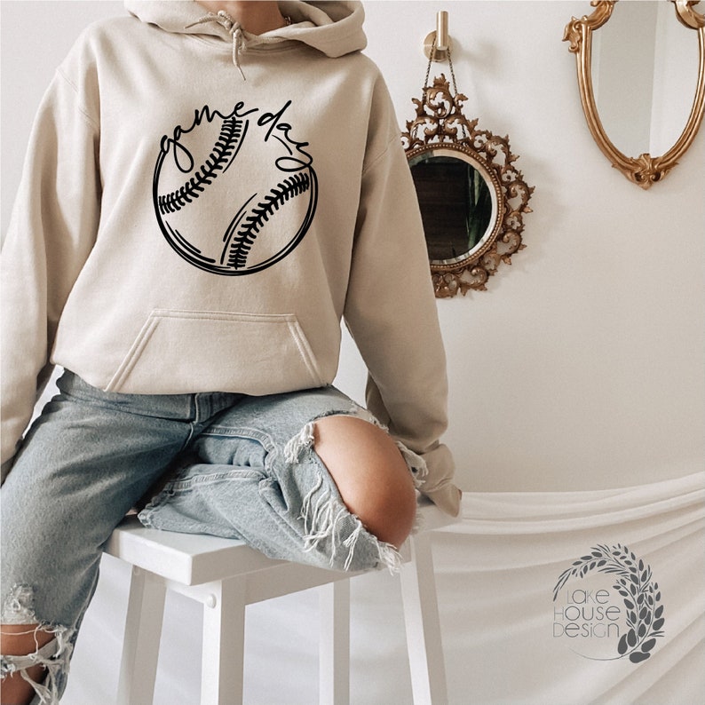 May include: A beige hoodie with a black baseball graphic and the text "game day" printed on the front.