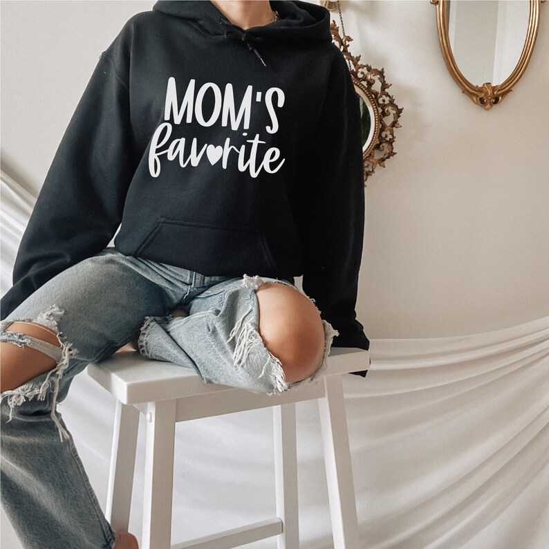 May include: A black hooded sweatshirt with the text "MOM'S favorite" in white with a small heart symbol.