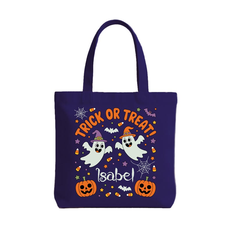 May include: A dark blue tote bag with a Halloween theme. The bag features two cartoon ghosts wearing witch hats, the text "Trick or Treat!", and two orange jack-o'-lanterns. The name "Isabel" is also printed on the bag.