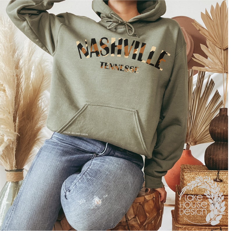 May include: A green hooded sweatshirt with the text "Nashville Tennessee" in a brown and tan animal print design.